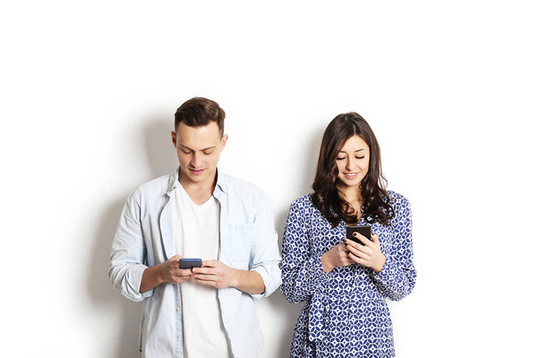 Young couple checking mobile phone, reading a message. Technology & relationship concept. Modern romance troubles. Male & female online dating app. Touch screen, chatting, swiping, browsing, surfing. - Valokuva, kuva