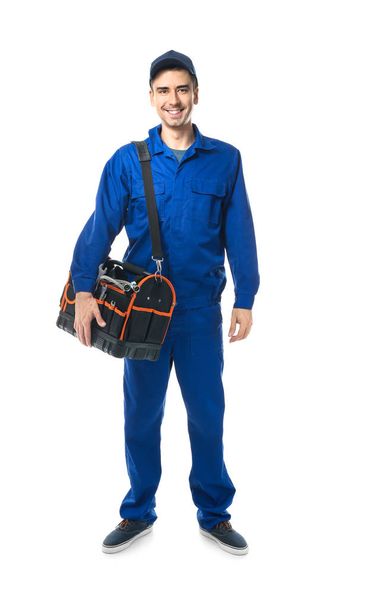 Young plumber in uniform with tool bag on white background - Фото, зображення