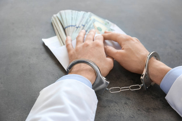 Doctor in handcuffs with bribe at workplace - Zdjęcie, obraz