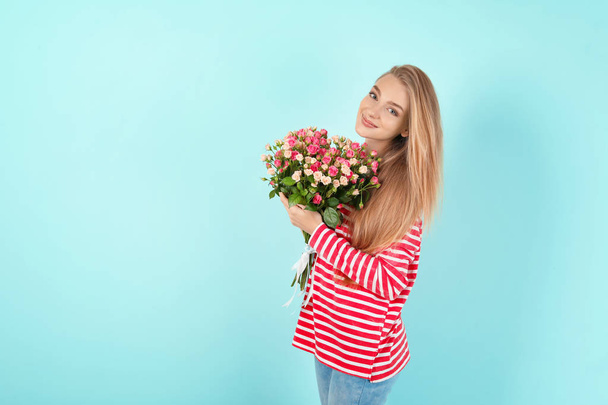 Beautiful young woman with bouquet of roses on color background - Фото, зображення