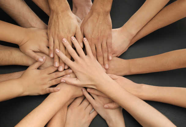 Groupe de personnes mettant les mains ensemble comme symbole d'unité
 - Photo, image