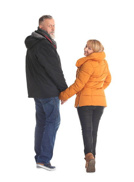 Mature couple in warm clothes walking on white background - Фото, зображення