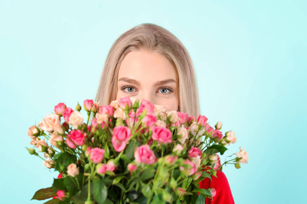 Beautiful young woman with bouquet of roses on color background - Foto, Imagem