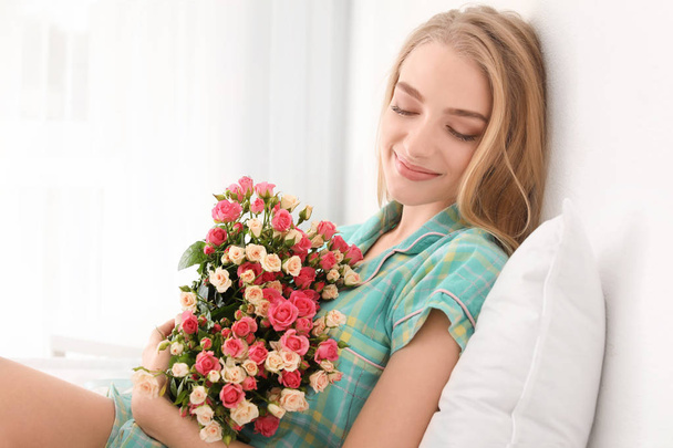 Beautiful young woman with bouquet of roses at home - Fotografie, Obrázek
