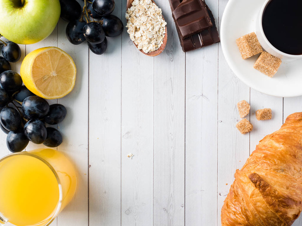 Breakfast on a White Table Coffee Croissant Orange juice Grapes Apple Chocolate Copy Space for Text - Foto, afbeelding