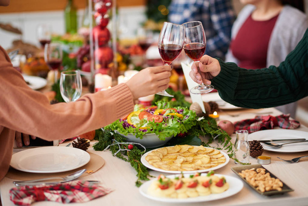 Menschen klappern Gläser mit Wein beim Weihnachtsessen - Foto, Bild