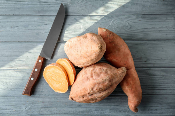 Sweet potatoes with slices on wooden table - Foto, afbeelding