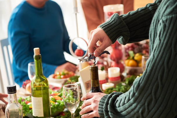 Ręce osoby otwierające się butelki wina na świąteczny obiad - Zdjęcie, obraz