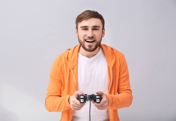 Happy man with video game controller on grey background - Zdjęcie, obraz