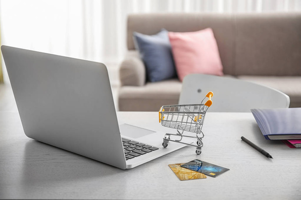 Laptop, small shopping trolley and credit cards on table. Internet shopping concept - Valokuva, kuva