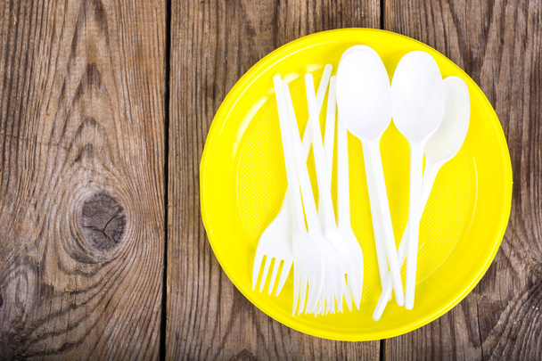 Plastic disposable tableware on wooden table - Photo, Image