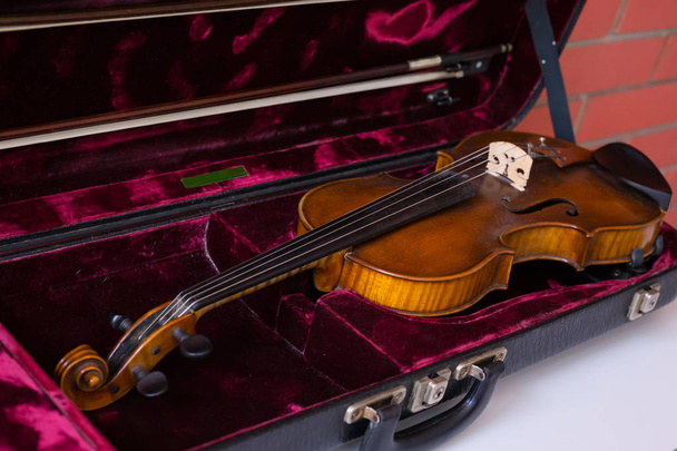 Скрипка и лук в темно-красном футляре
. - Фото, изображение