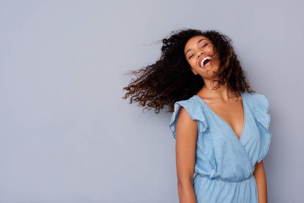 Porträt einer fröhlichen jungen afrikanisch-amerikanischen Frau mit lockigem Haar, die lacht  - Foto, Bild