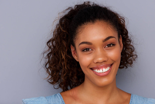 Közelről sötétszürke háttérrel mosolygó csinos afroamerikai lány portréja - Fotó, kép