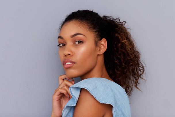 Retrato lateral de la hermosa joven afroamericana contra la pared gris
 - Foto, Imagen