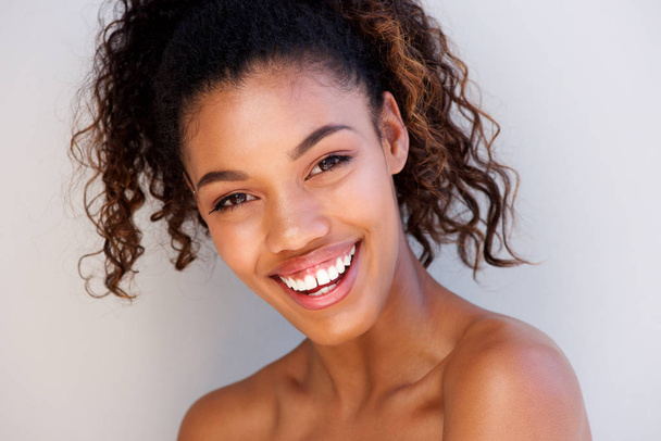 Close-up van portret van aantrekkelijke jonge vrouw die lacht tegen witte achtergrond  - Foto, afbeelding