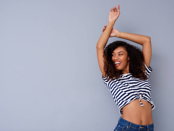 Portrait of attractive african woman smiling with arm raised - Photo, image