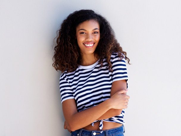 Портрет впевненої молодої чорної жінки, яка посміхається на білій стіні
 - Фото, зображення