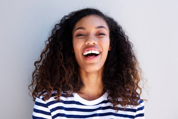 Close up retrato de feliz jovem afro-americana rindo contra a parede branca
 - Foto, Imagem