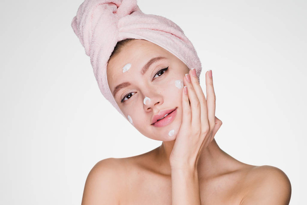 woman with towel on her head after shower applied cream on face - Foto, Imagen