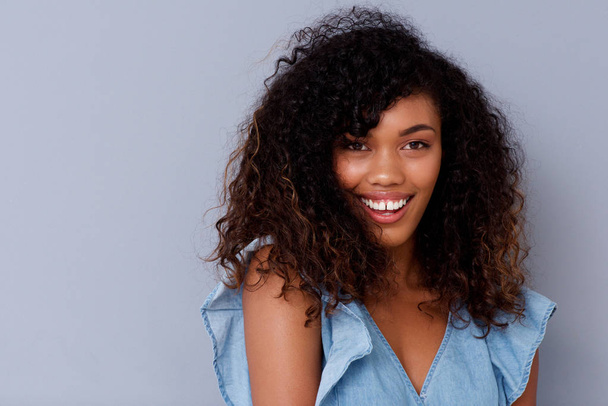 Primer plano retrato de hermosa joven afroamericana sonriendo contra la pared gris
 - Foto, imagen