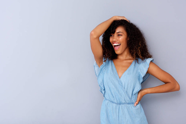 灰色の背景に対して笑っている陽気な若いアフリカ系アメリカ人女性の肖像画 - 写真・画像