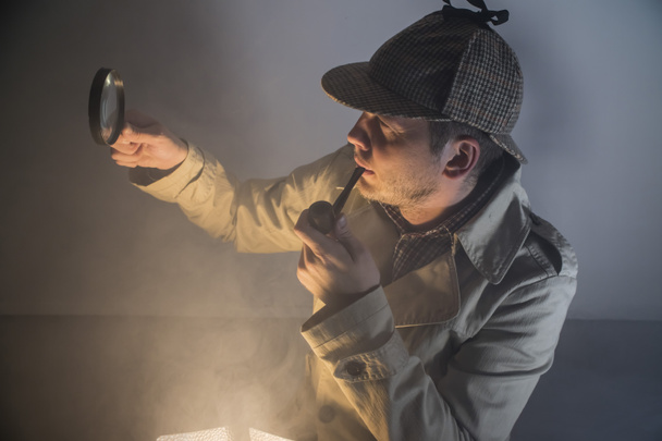 Sherlock holmes v studio detektiv při práci s zvětšovací sklo a trubky - Fotografie, Obrázek