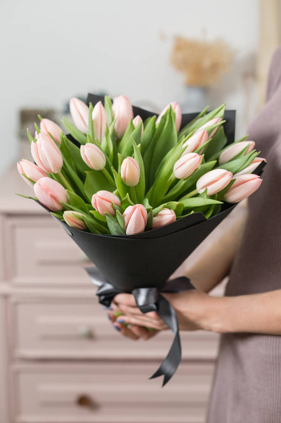 piękny, luksusowy bukiet kwiatów różowe tulipany w ręce kobiety. Praca w kwiaciarni Kwiaciarnia. - Zdjęcie, obraz