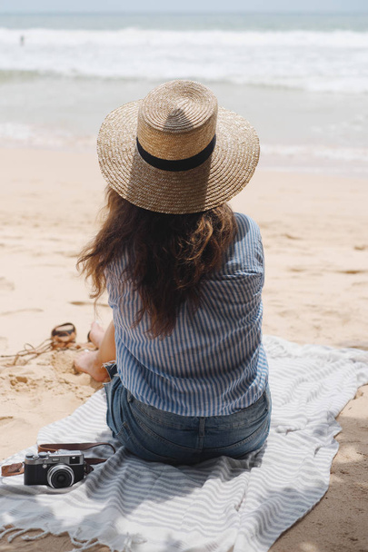Girl in hat on the beach looking at the ocean - Fotoğraf, Görsel