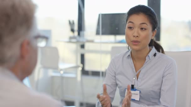 4k Audiologie Arzt zeigt dem Patienten ein modernes High-Tech-Hörgerät und erklärt - Filmmaterial, Video