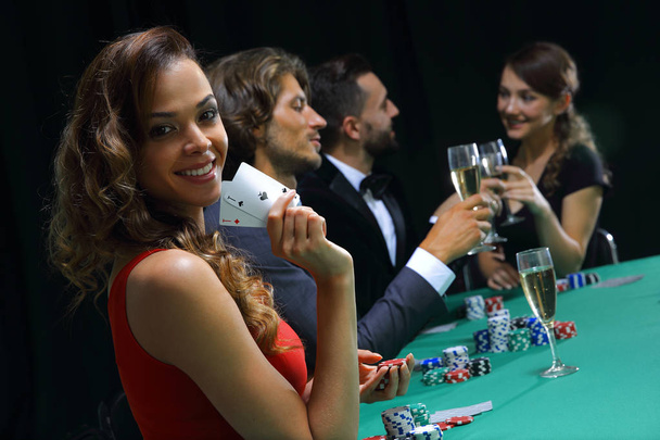 young brunette woman playing poker on black background - Foto, Imagen