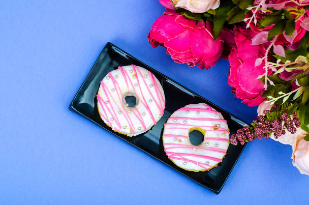 Two fresh round donuts on black plate - 写真・画像