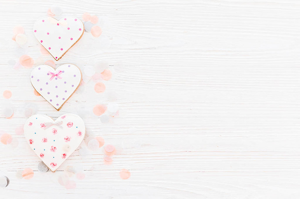 cookie ροζ καρδιές σε φόντο λευκό ρουστίκ ξύλινα με κομφετί σε απαλό φως. ημέρα της μητέρας ευχετήρια κάρτα. χώρο για το κείμενο. Happy Ημέρα του Αγίου Βαλεντίνου ή γυναικών. μακέτα - Φωτογραφία, εικόνα