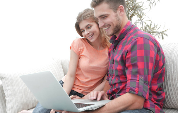 sorridente giovane coppia con computer portatile seduto sul divano
 - Foto, immagini