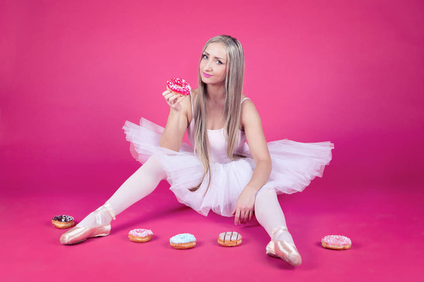 Ballerina in tutu rok eten van een donut - Foto, afbeelding