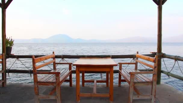 Taras z drewnianym stołem i krzesłami z widokiem na morze. - Materiał filmowy, wideo