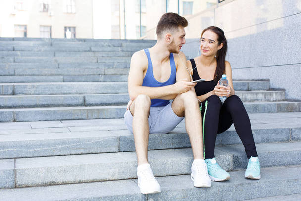 Mujer y hombre eligen la música para escuchar durante el jogging
 - Foto, Imagen