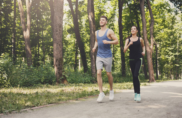 junges Paar joggt im grünen Park, kopiert Raum - Foto, Bild