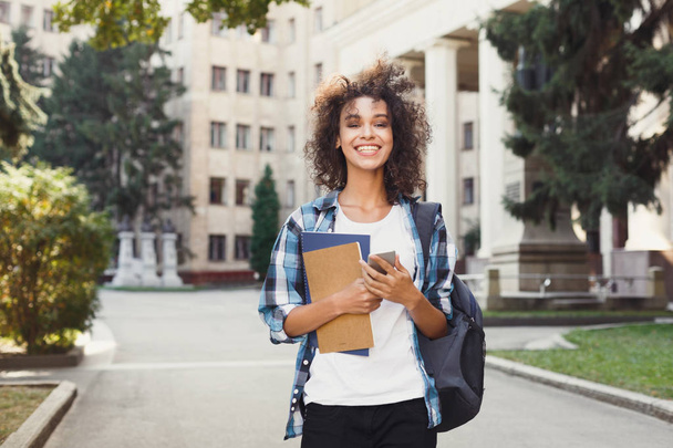 Student girl with backpack and mobile at university building background - Photo, Image