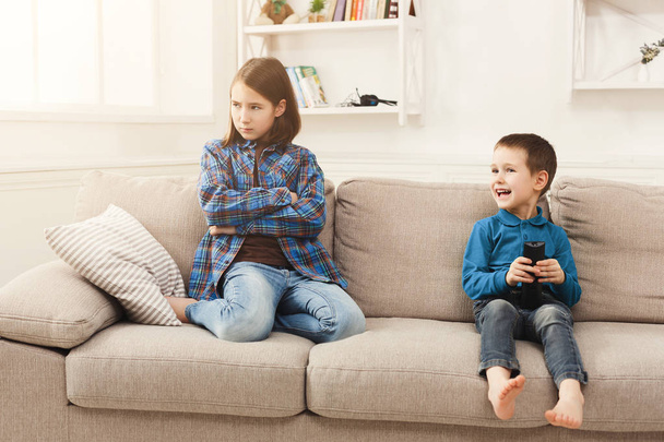 Two kids with remote control on couch at home - Fotó, kép
