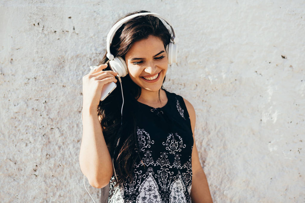 Young woman listening to music via headphones on the street - Фото, зображення