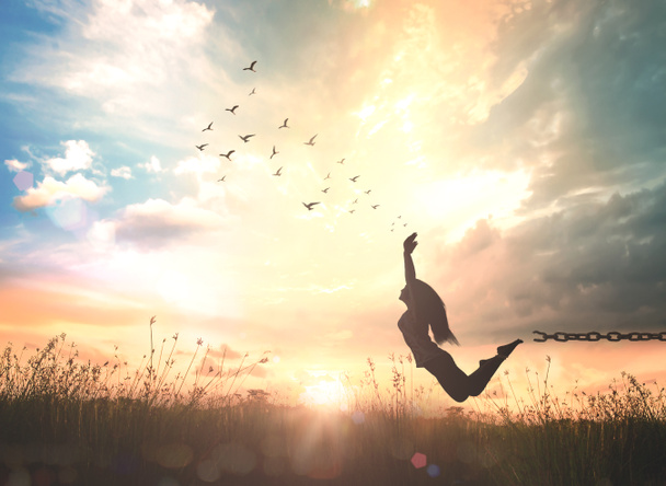 世界精神衛生デーのコンセプト:彼女の手を上げて秋の日没の牧草地でジャンプする女の子のシルエット - 写真・画像