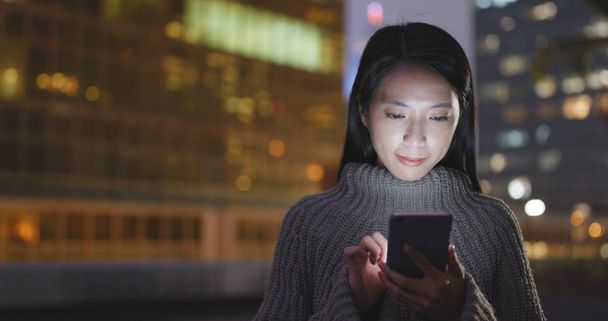 Mujer enviando sms en el teléfono celular por la noche
  - Foto, imagen