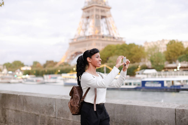 Młoda kobieta stojąc na nasyp w Paryżu i oglądanie zdjęć - Zdjęcie, obraz
