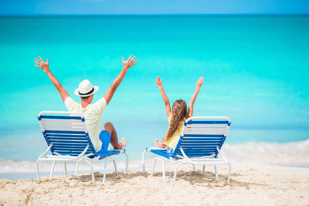 Père et fille mains en l'air sur la plage assis sur chaise longue
 - Photo, image
