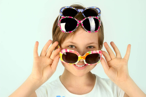 Lähikuva muotokuva pikkutyttö yllään funky aurinkolasit. Nuori teini tyttö yllään tyylikäs aurinkolasit. Suloinen tyttö yllään aurinkolasit
. - Valokuva, kuva