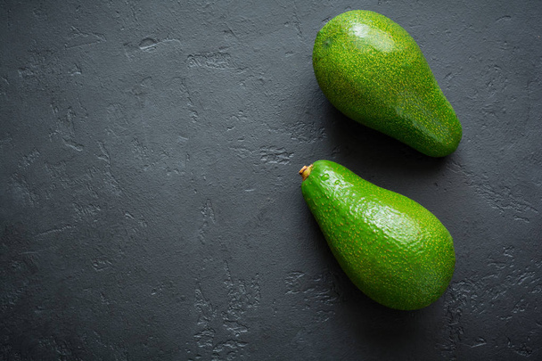 Raw fresh avocado on dark old concrete or stone background. Selective focus. Top view.  - Photo, image