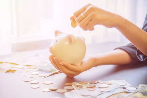 Piggy bank in hand with cash pile. - Photo, Image