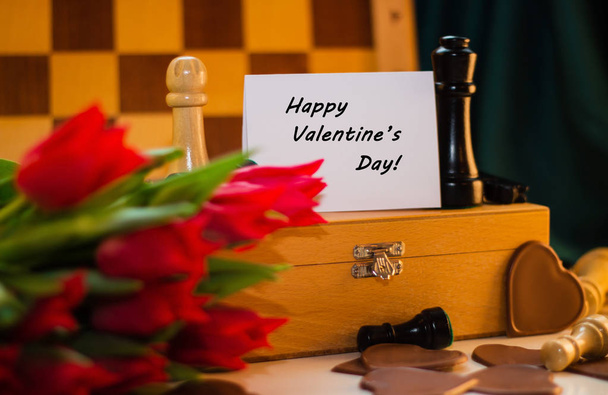Buquê de tulipas vermelhas, corações de chocolate e xadrez com tag
 - Foto, Imagem