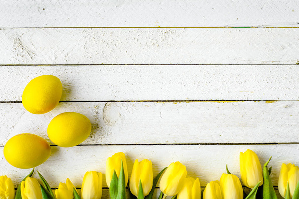 Spring tulips and yellow easter eggs on white wooden background - Photo, image